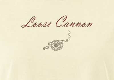 Loose Cannon women's tee — Buttermilk — small front script and cannon detail, literally cropped from supplier digital mockup; Women's Heavyweight Garment Dye Tee | Bella + Canvas 6110GD Buttermilk; supplier digital mockup.